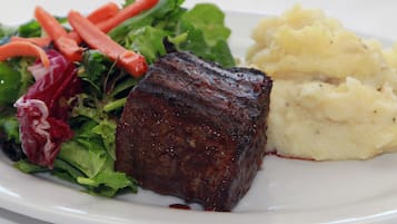 A plate with a steak, a side of mashed potatoes, and a mixed green salad with carrots.