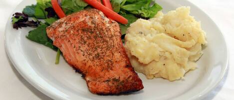 A plate with salmon, mashed potatoes, and a mixed green salad.