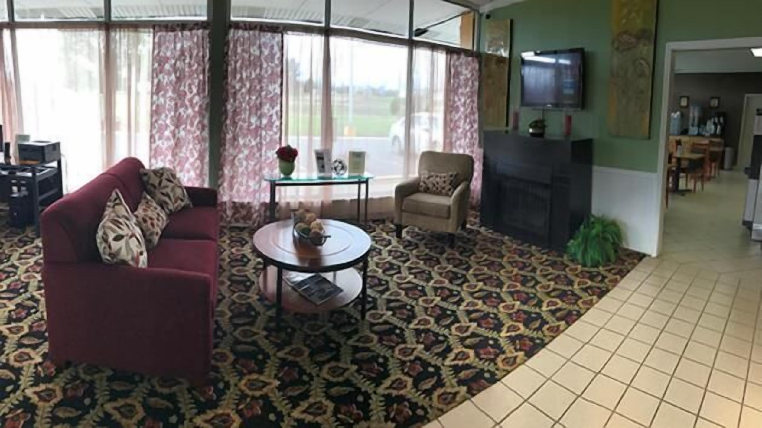 A living room with a sofa, armchair, and coffee table, a fireplace, and a television.