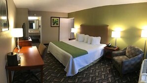 A hotel room with a bed, a desk, a chair, a lamp, and a mirror. - Wingfield Inn (Mayfield)