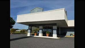 A building with a flat roof, a large sign with a letter 'W' on top, and a covered entrance area with potted plants. - Wingfield Inn (Mayfield)