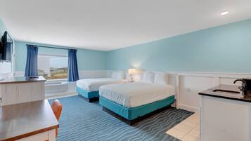 Une chambre d’hôtel avec deux lits, un bureau, un lavabo et une vue sur l’extérieur.