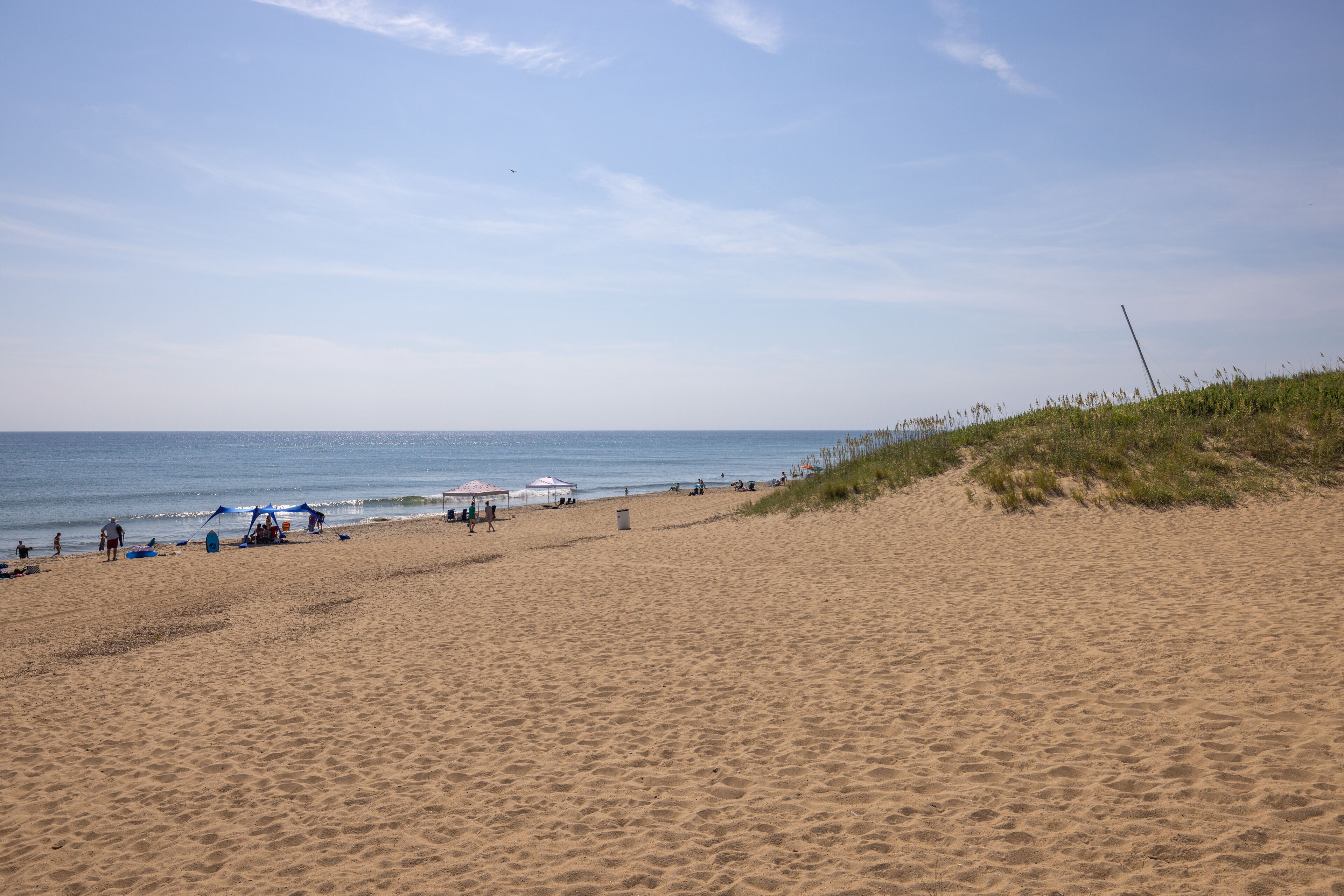 A wide sandy beach with a clear sky and calm sea.