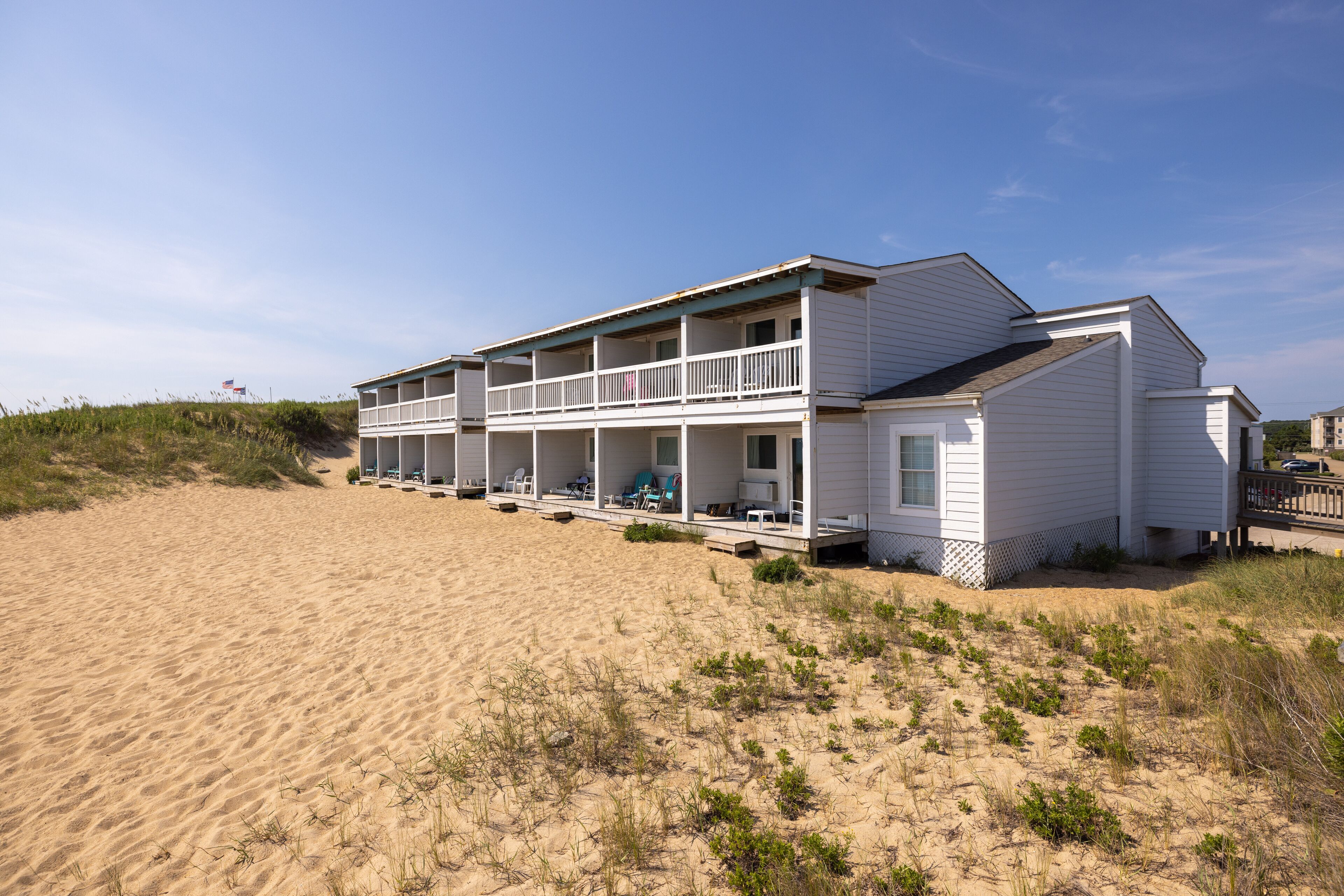 Une maison de plage à deux étages, dotée d’un balcon et d’une véranda couverte.