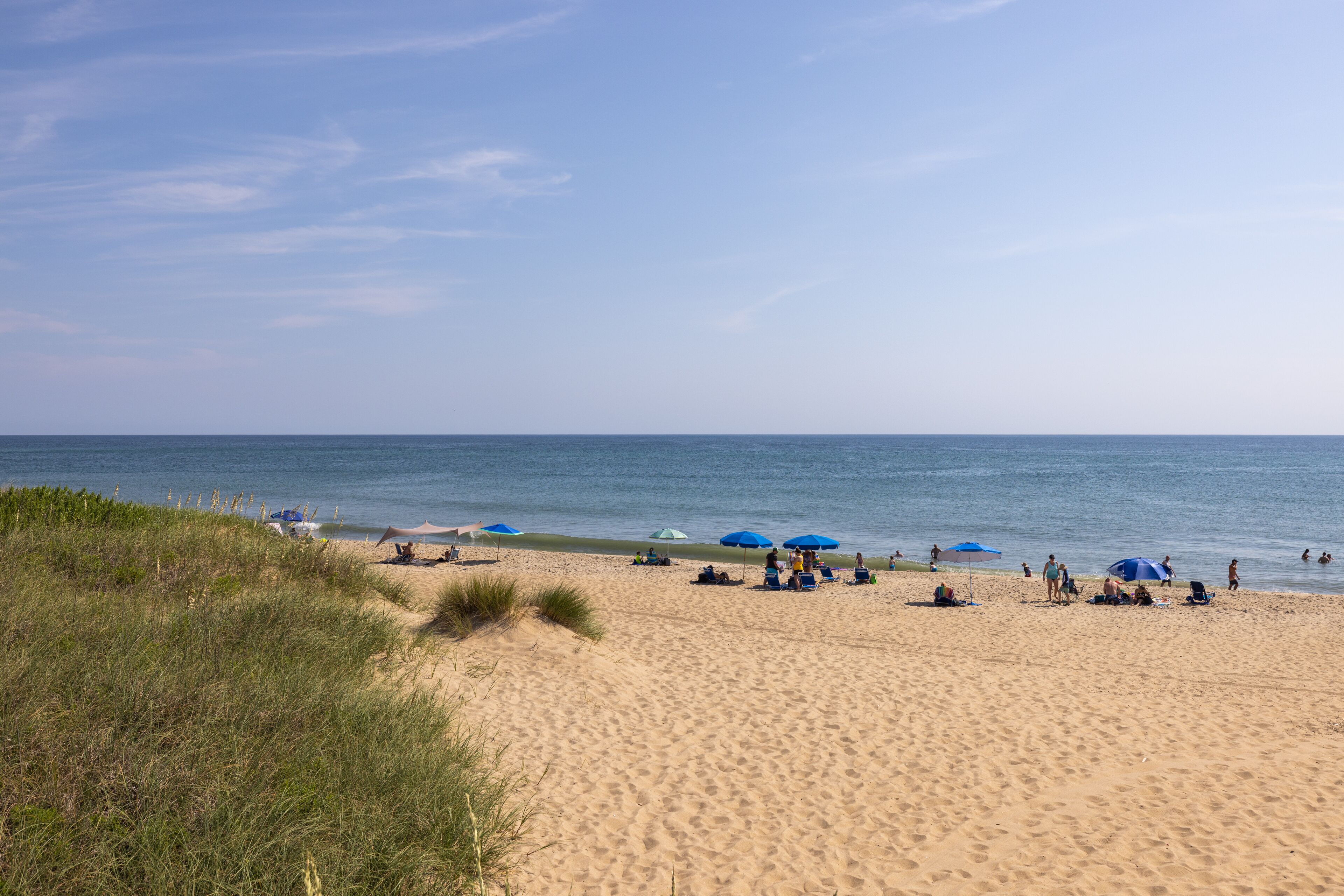 A sandy beach with people and umbrellas.