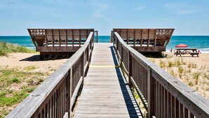 Una pasarela de madera que lleva a cabañas de playa con vista despejada al océano.