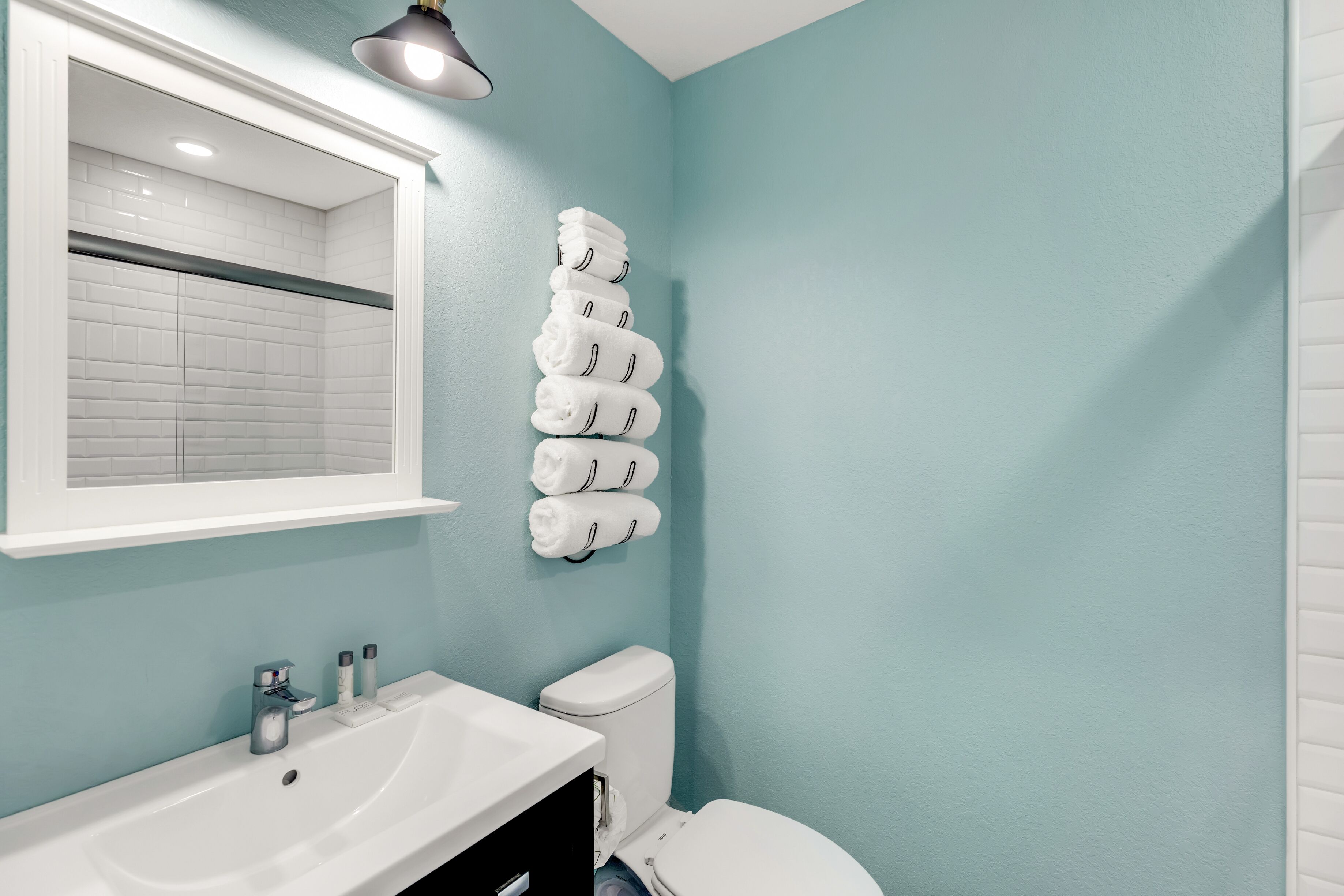 A bathroom with a white sink, a toilet, and a wall-mounted towel rack with folded towels.