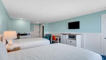 A hotel room with two beds, a desk, a chair, a TV, and a kitchenette.