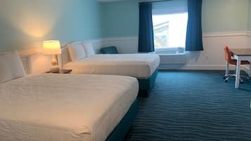 A hotel room with two beds, a desk, a chair, and a window with curtains.