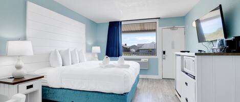 Una habitación de hotel moderna con una cama grande, un escritorio, un televisor y vistas a la ciudad.