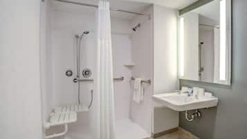 A bathroom with a shower, a sink, and a mirror.