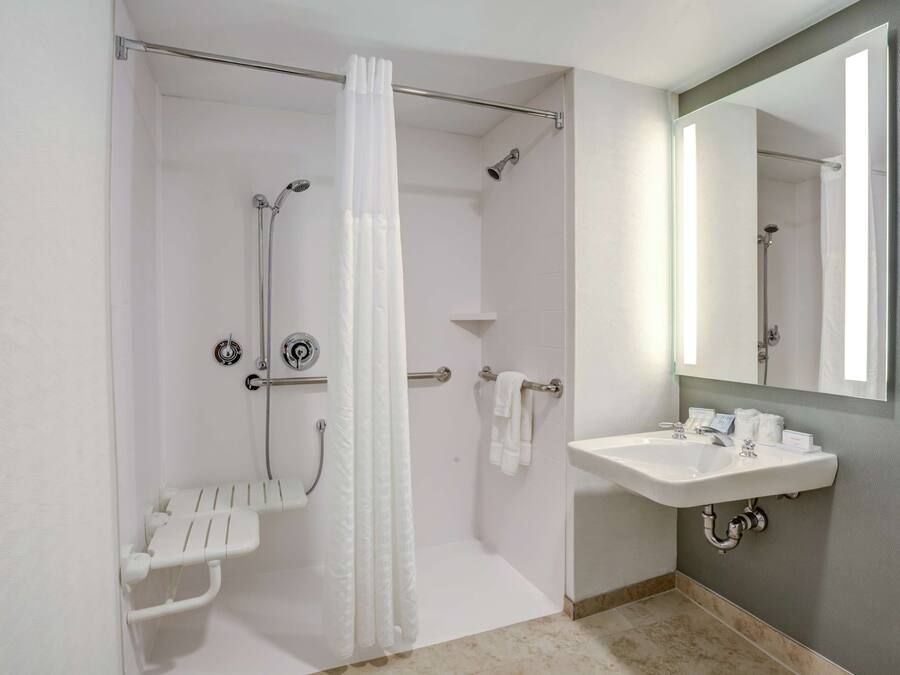 A bathroom with a shower, a sink, and a mirror.