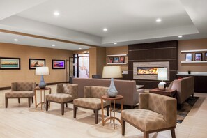 A hotel lobby with seating, a fireplace, and framed pictures on the walls.