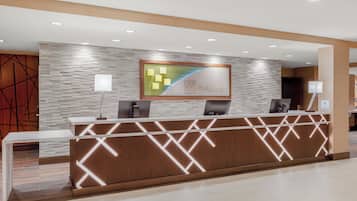 Ein Hotel-Rezeptionsschalter mit modernem Design, einem Logo und einem digitalen Bildschirm.