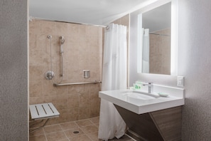 Un baño moderno con ducha, lavamanos y espejo.