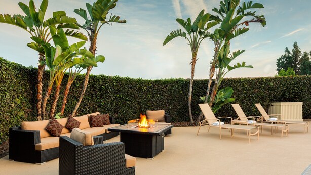 Eine Terrasse im Freien mit einer Sofagarnitur, Liegestühlen und einem Feuerkorb.
