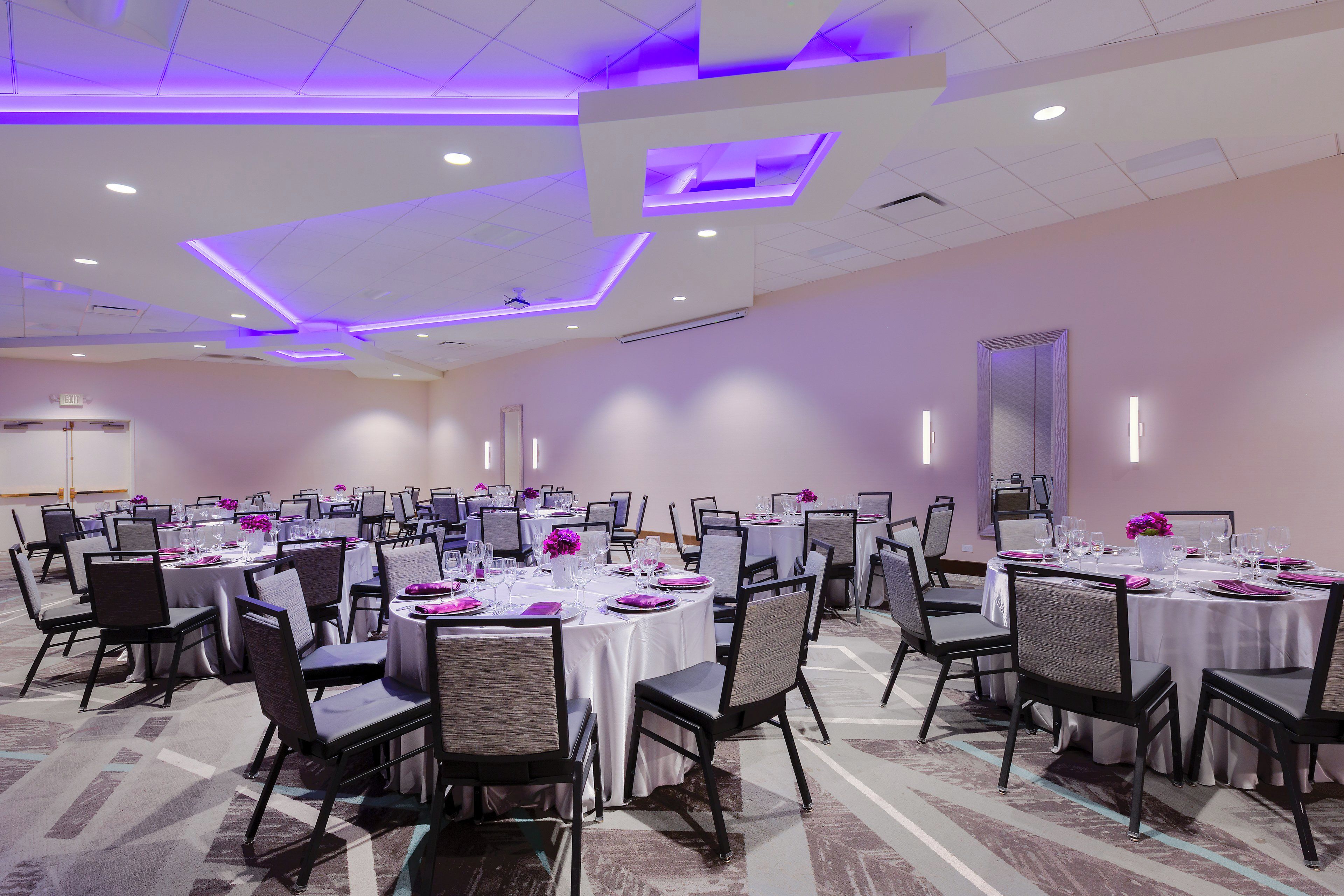 A conference room with multiple tables set for dining, equipped with chairs and tables.