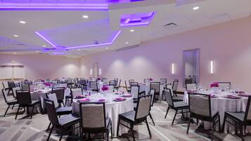 A conference room with multiple tables set for dining, equipped with chairs and tables.