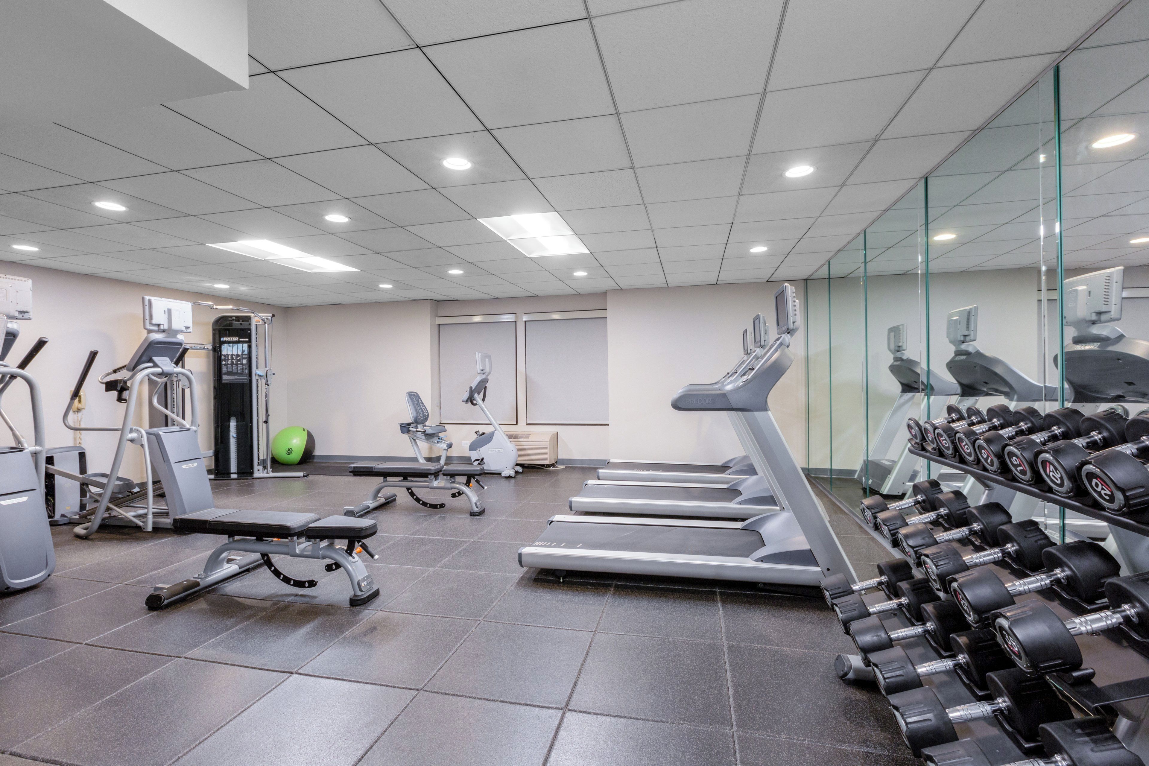 Een sportschool met loopbanden, gewichten en trainingsapparatuur.