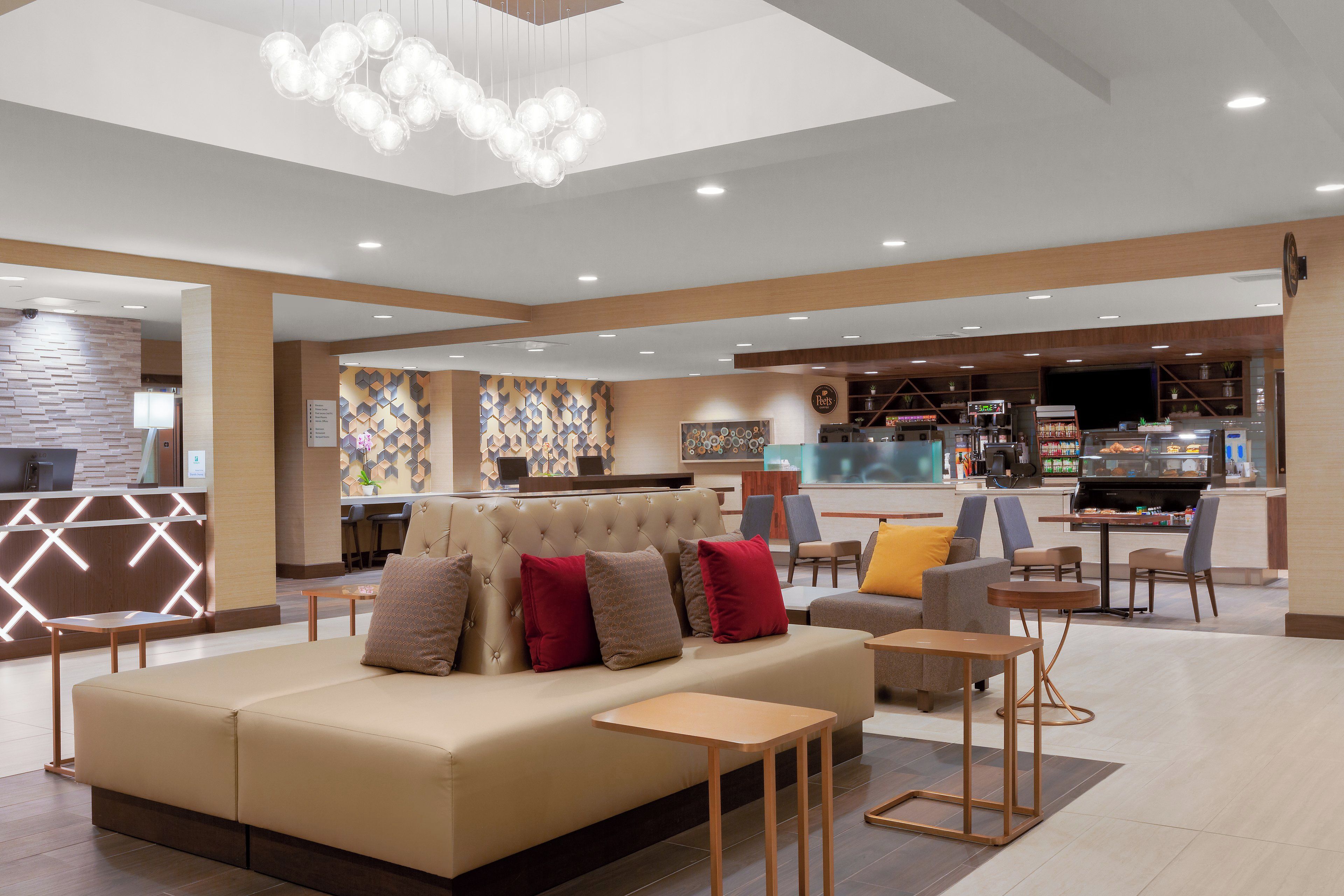 Un moderno vestíbulo de hotel con zona de estar, mostrador de recepción y bar.