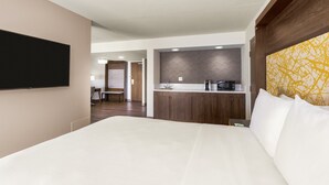 Ein Hotelzimmer mit einem großen Bett, einem an der Wand montierten Flachbildfernseher, einer Küchenzeile mit einer Mikrowelle und einer Wand mit Zickzackmuster.