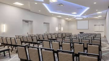 A conference room with rows of chairs, a projector screen, and a whiteboard.