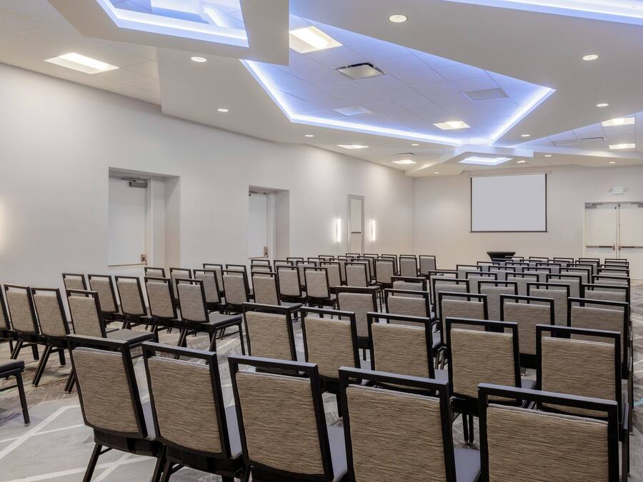 A conference room with rows of chairs, a projector screen, and a whiteboard.