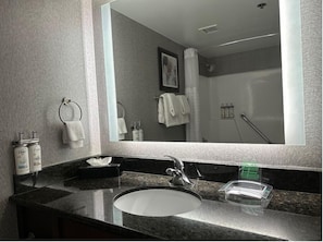 Un baño moderno con un espejo grande, un lavamanos y una ducha.