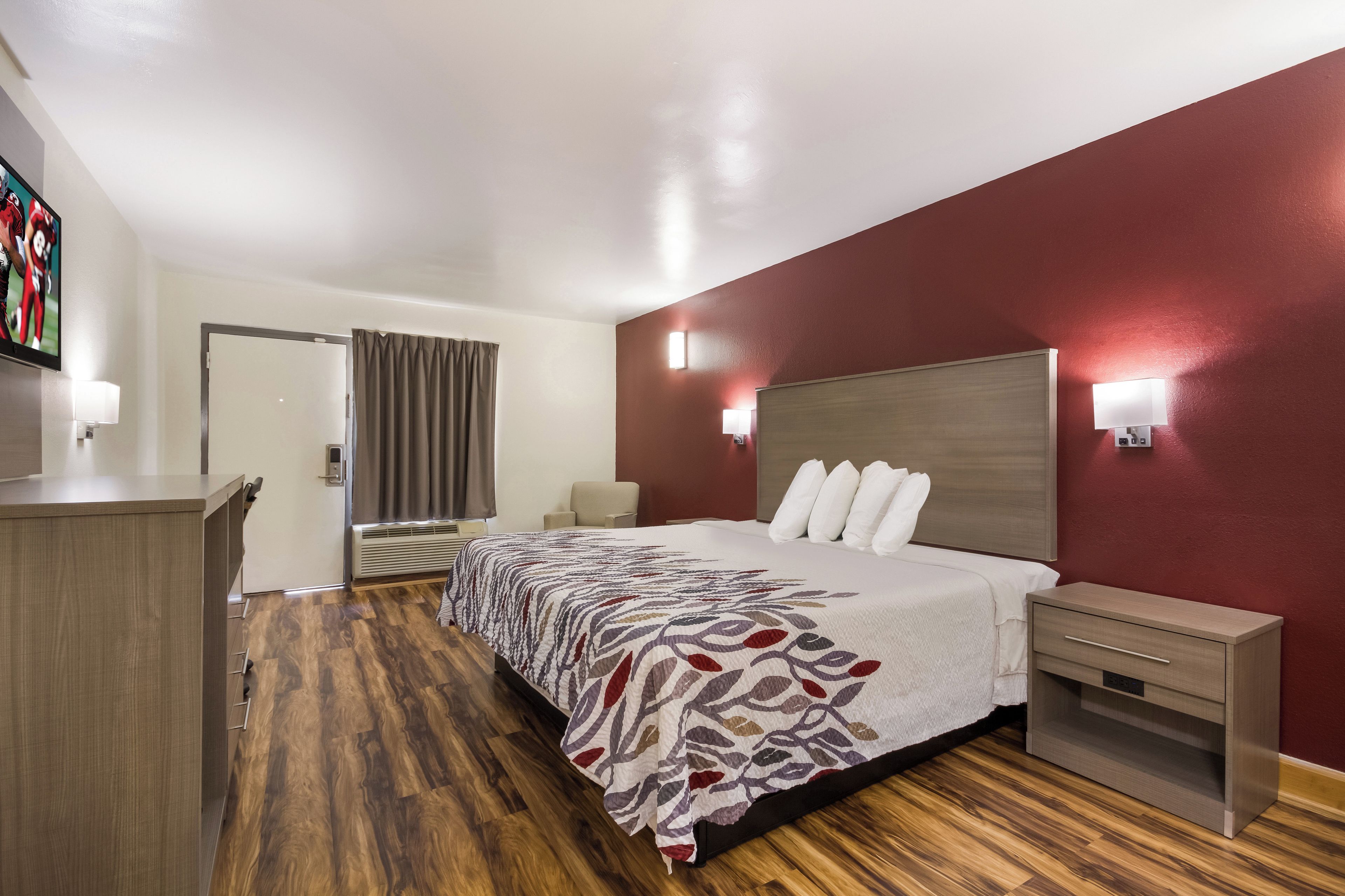 Una habitación de hotel con cama, mesitas de noche, escritorio y televisor.