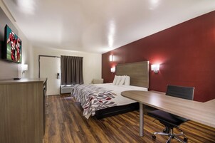 A hotel room with a bed, desk, chair, and a television on the wall.