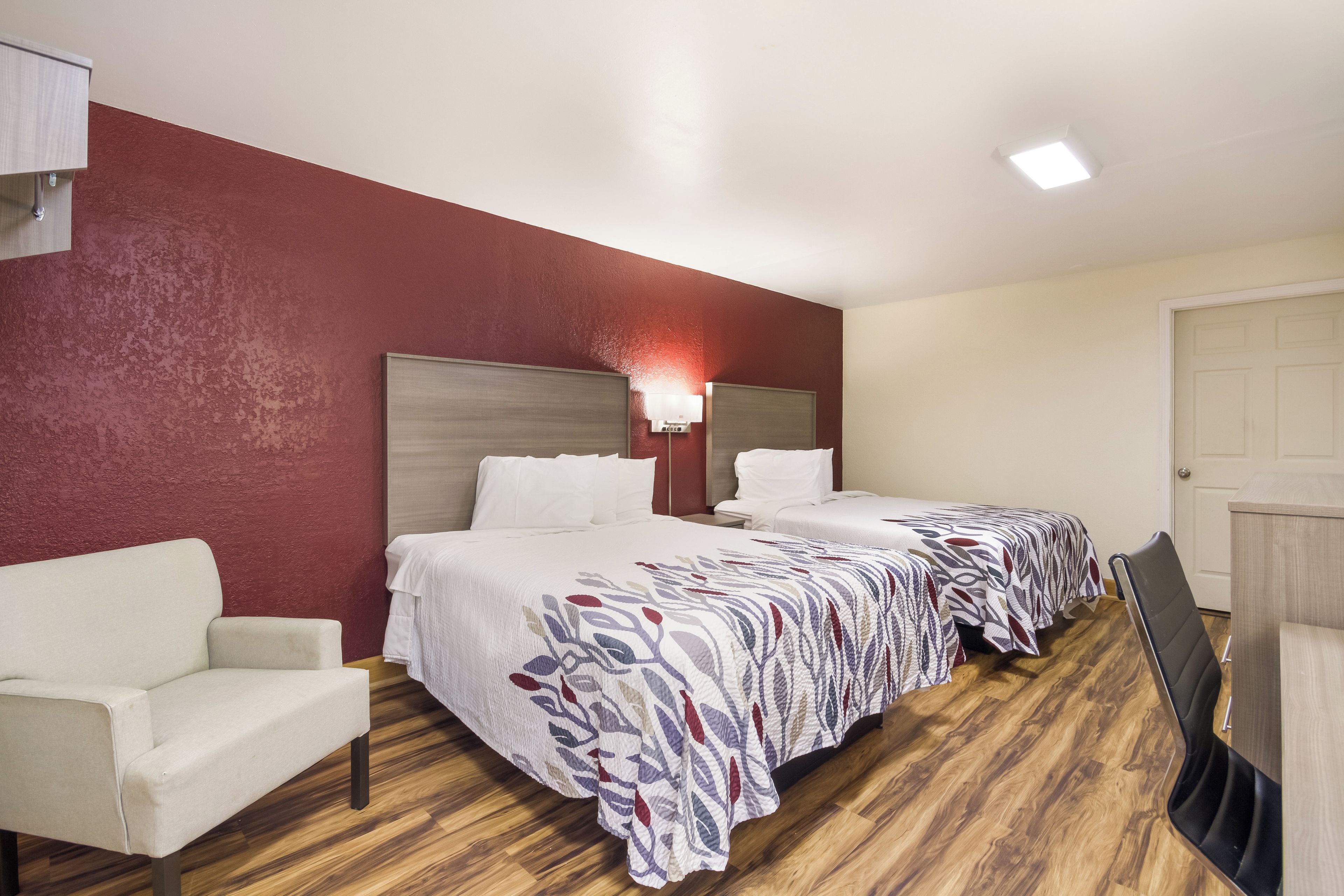 Une chambre d’hôtel avec deux lits, une chaise, un bureau et une porte.