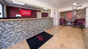 A hotel reception area with a modern design, including a reception desk, a digital screen advertising free Wi-Fi, and a Red Roof Inn sign. - Red Roof Inn Crestview (Crestview)