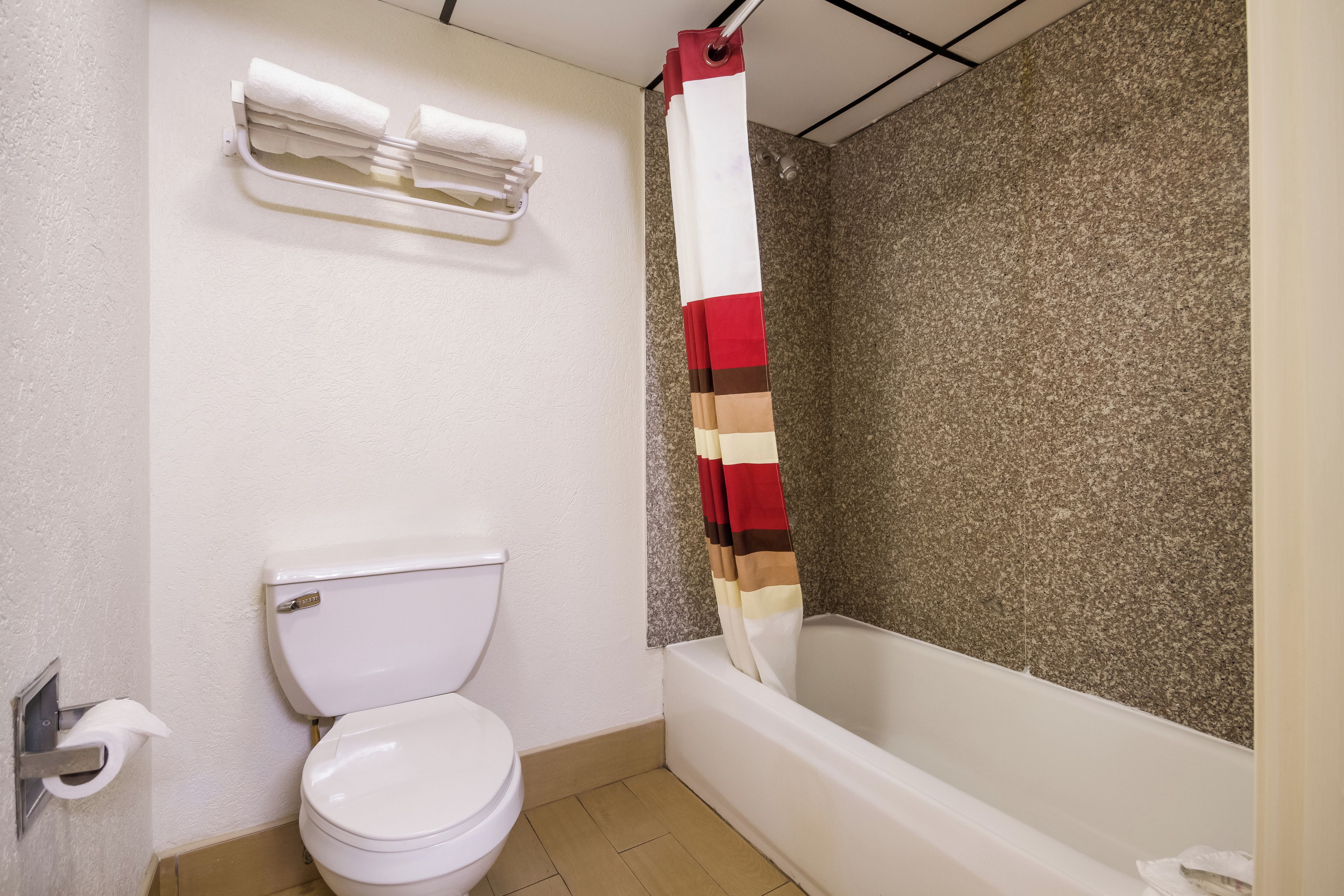 A bathroom with a toilet, a towel rack, and a shower curtain.