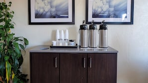 A kitchenette with a coffee maker, creamer, and thermos on the counter, and two framed abstract paintings on the wall. - Red Roof Inn Crestview (Crestview)