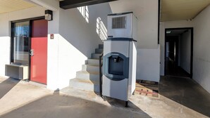 A building entrance with a red door, a staircase, and a water dispenser. - Red Roof Inn Crestview (Crestview)