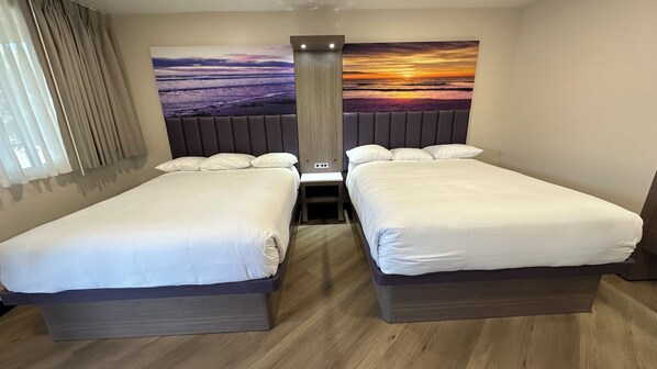 A hotel room with two beds, a large wall mural of a sunset, and a modern design.