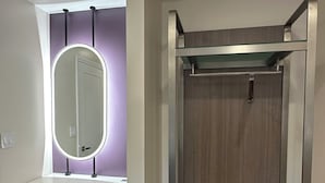 A modern bedroom with a bunk bed, a vanity with a mirror, and a small seating area.