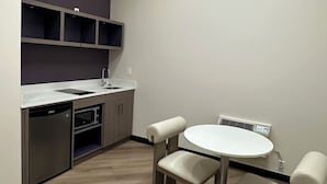 A modern kitchen with a skylight, built-in appliances, and a dining area with a round table and cushioned chairs.