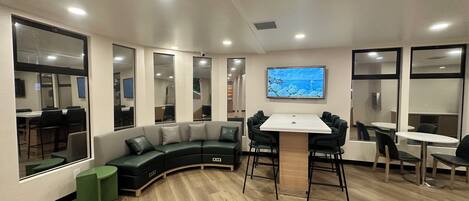 A conference room with a curved seating area, a central table, and a television mounted on the wall.