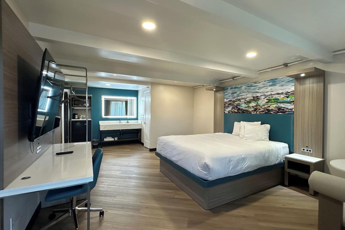 A modern hotel room with a bed, desk, chair, and a TV.