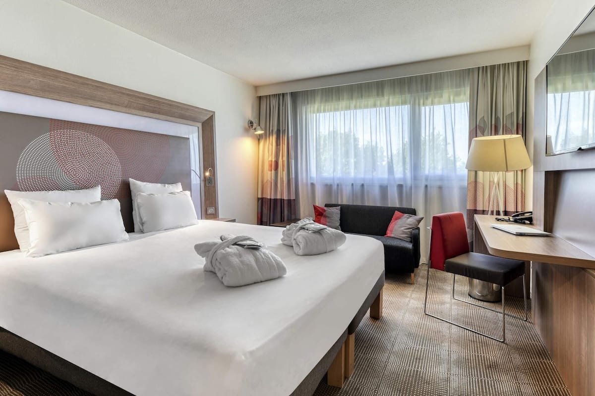 Une chambre dâhĂŽtel avec un grand lit, un bureau, une chaise et un canapĂ©.