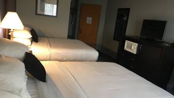 Ein Hotelzimmer mit zwei Betten, einem Fernseher, einer Kommode und einer Lampe.