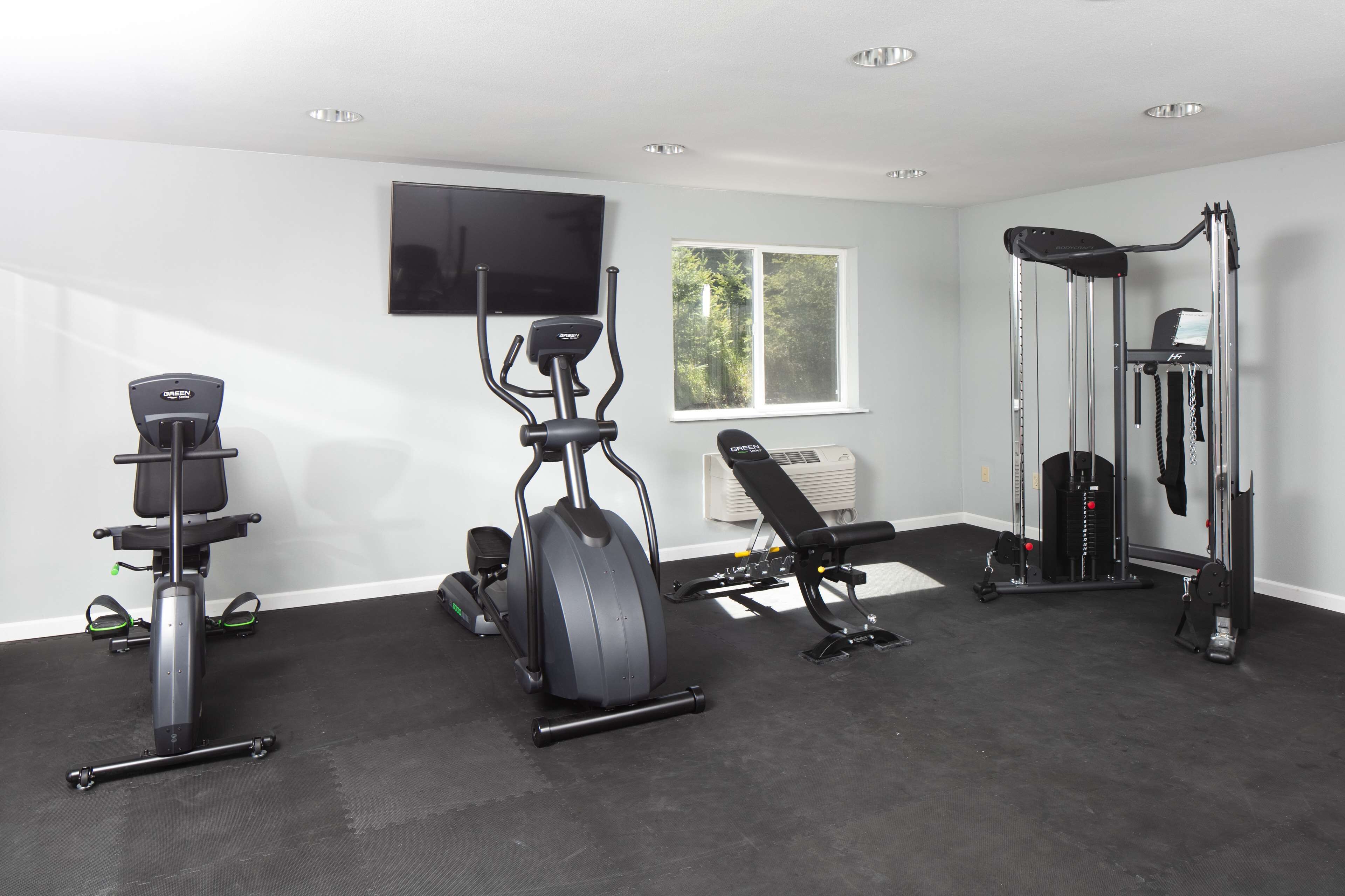 A home gym with a stationary bike, elliptical, bench press, and weight machine.