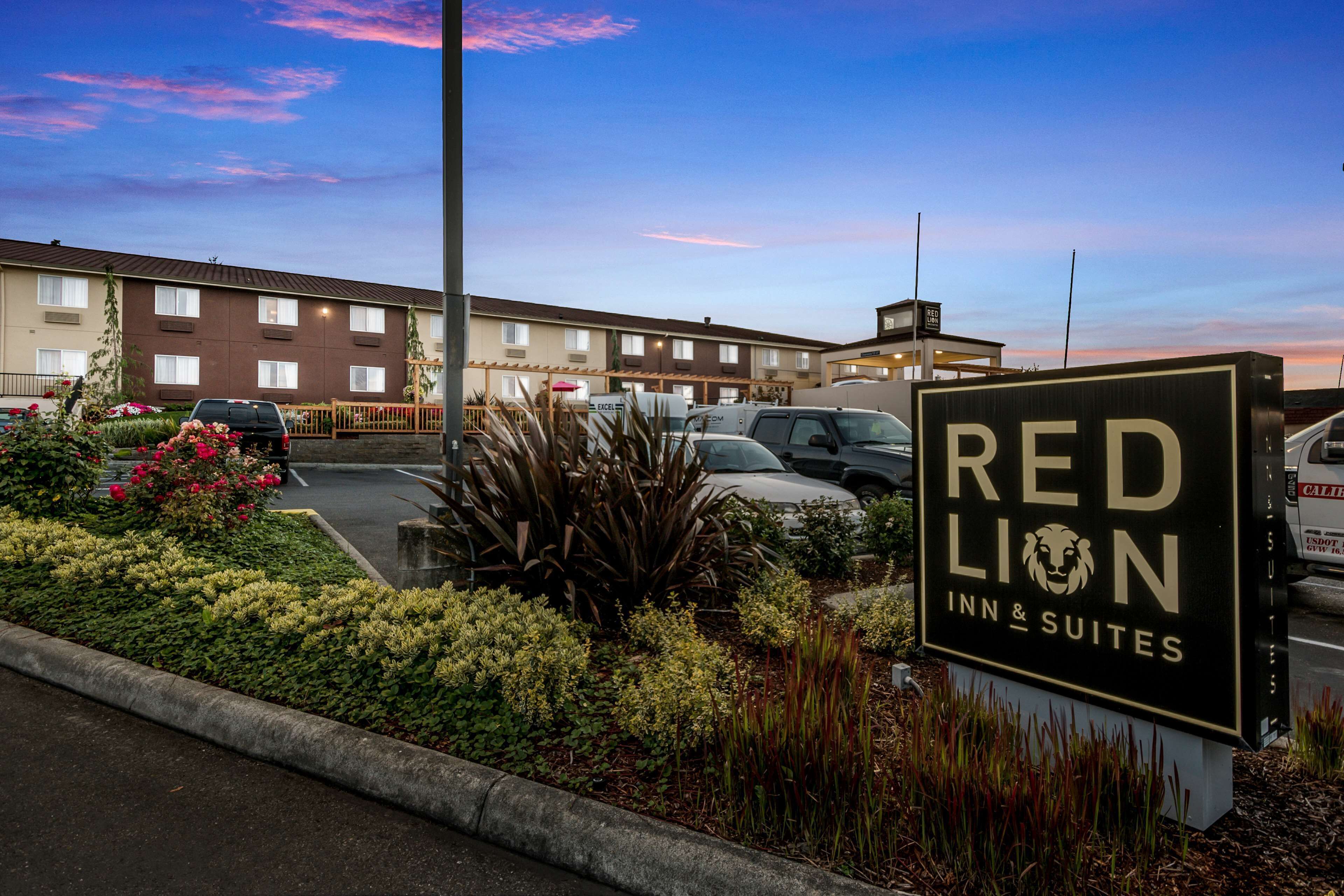 Schild des Red Lion Inn & Suites mit einem Parkplatz und einem Gebäude im Hintergrund.