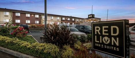 Schild des Red Lion Inn & Suites mit einem Parkplatz und einem Gebäude im Hintergrund.