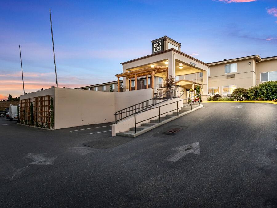 Un hotel con entrada cubierta, una escalera que conduce al vestíbulo y un área de estacionamiento.
