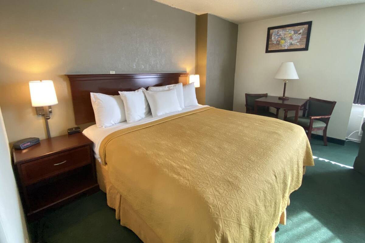 Une chambre d’hôtel avec un grand lit, des lampes de chevet, un bureau et une chaise.