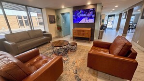 A modern living room with a large flat-screen TV, leather sofas, and a coffee table. - Baymont by Wyndham Great Falls City Center (Great Falls)