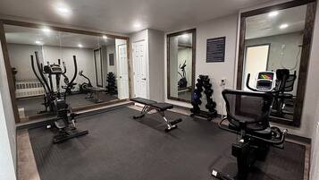 A gym with exercise equipment, a bench, and mirrors.