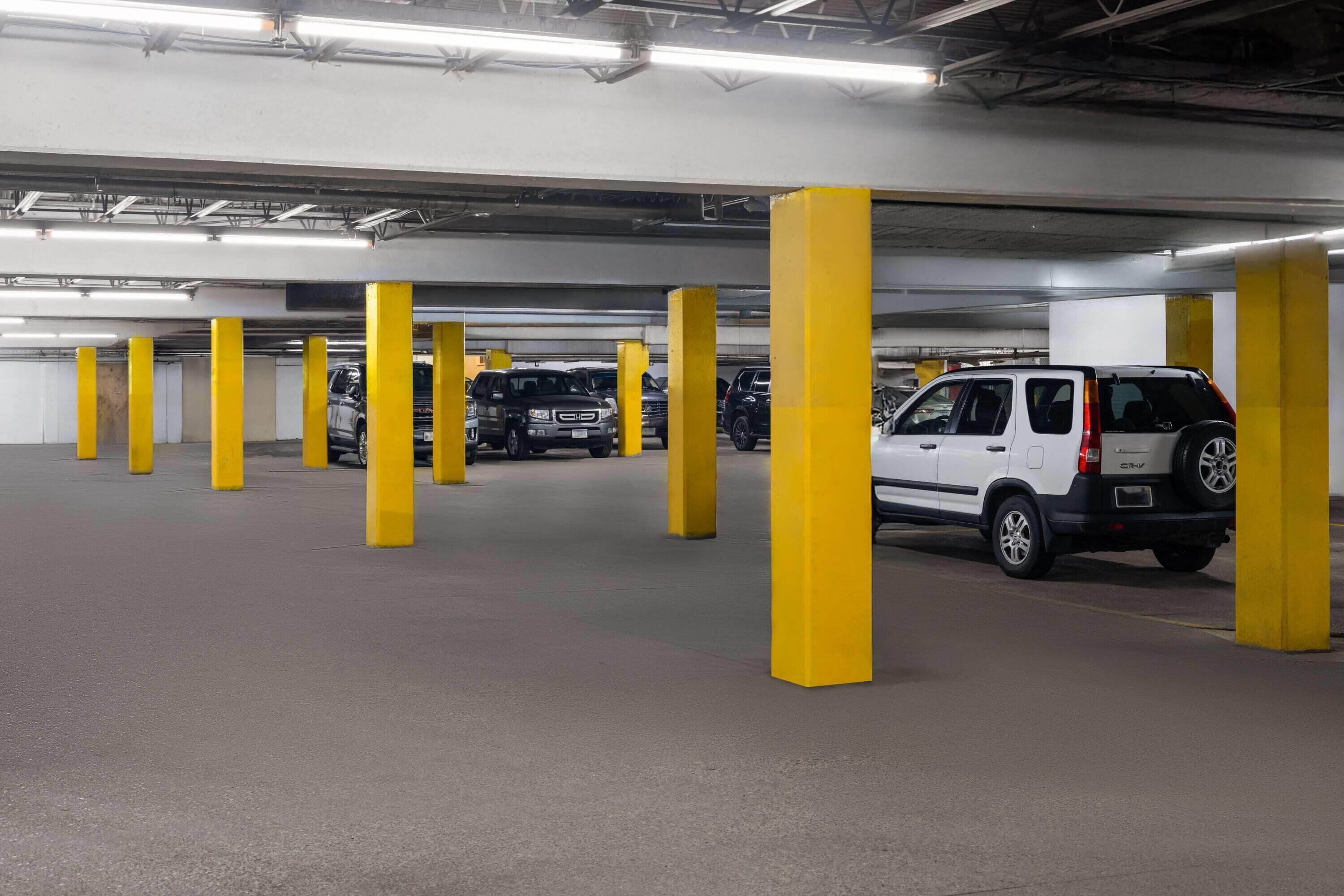Un estacionamiento de varios niveles con pilares amarillos y varios vehículos estacionados.